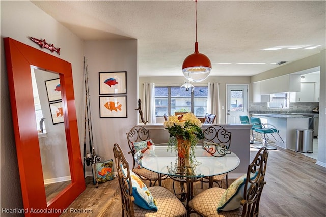 dining area featuring light hardwood / wood-style floors and a textured ceiling