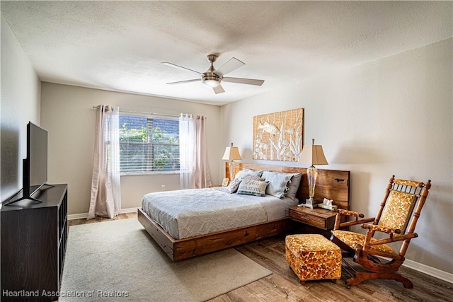 bedroom with ceiling fan, wood-type flooring, and a textured ceiling