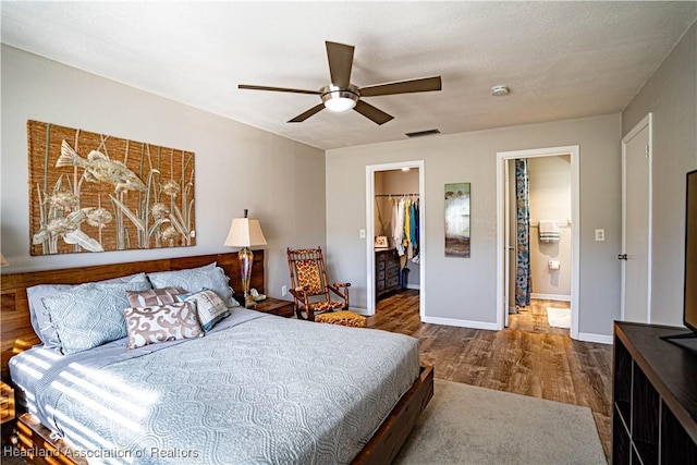 bedroom featuring ensuite bath, hardwood / wood-style flooring, ceiling fan, a spacious closet, and a closet