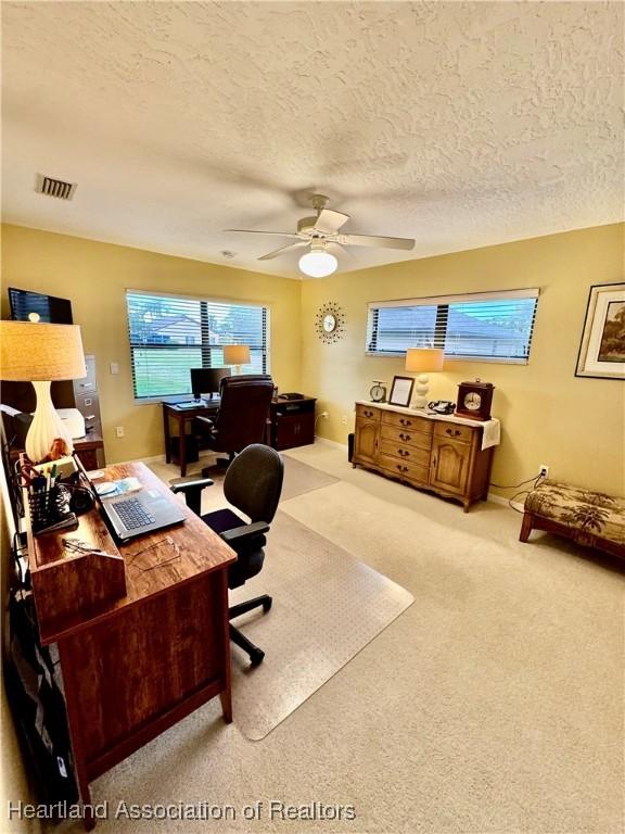 carpeted office space with ceiling fan and a textured ceiling