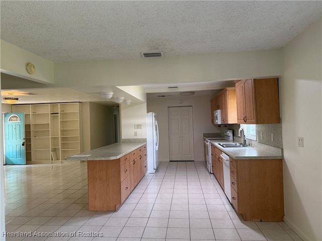 330 Sassafras Ave, Sebring, FL 33870 - kitchen featuring white appliances, a peninsula, light tile patterned flooring, a sink, and a textured ceiling