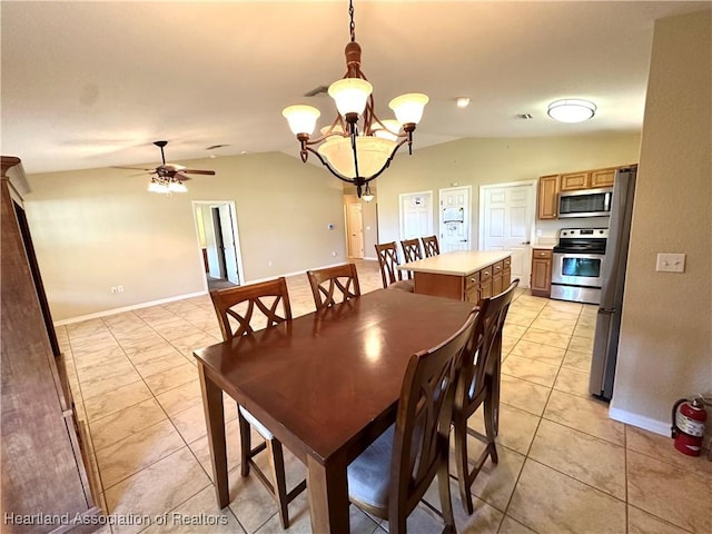 dining space with light tile patterned floors, ceiling fan with notable chandelier, baseboards, and vaulted ceiling