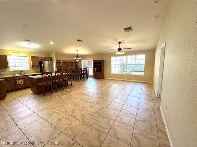 kitchen with visible vents, a sink, a kitchen island, freestanding refrigerator, and a breakfast bar area