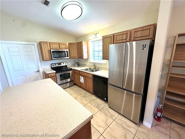 kitchen with visible vents, light countertops, vaulted ceiling, appliances with stainless steel finishes, and a sink