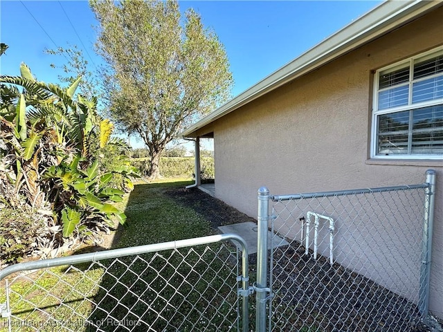 view of side of home with stucco siding, fence, and a gate