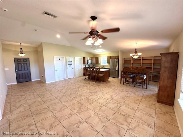 kitchen featuring visible vents, vaulted ceiling, appliances with stainless steel finishes, pendant lighting, and ceiling fan with notable chandelier