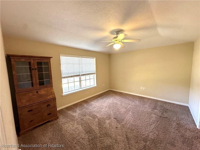 unfurnished room with dark colored carpet, baseboards, a textured ceiling, and ceiling fan