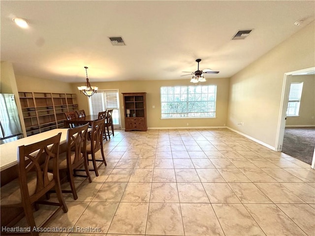 dining area featuring light tile patterned floors, visible vents, ceiling fan with notable chandelier, and baseboards