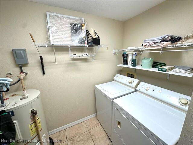 laundry area with baseboards, washer and clothes dryer, water heater, laundry area, and light tile patterned floors