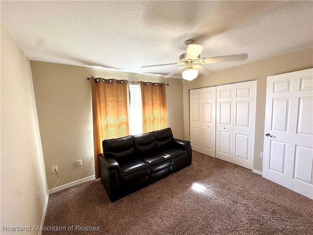 carpeted living room featuring ceiling fan, a textured wall, baseboards, and a textured ceiling