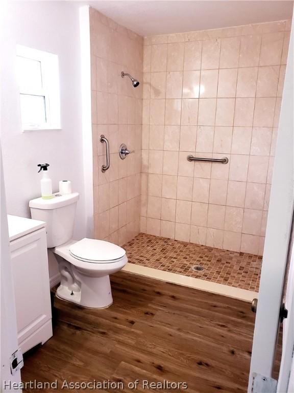 full bathroom featuring vanity, wood finished floors, a shower stall, and toilet