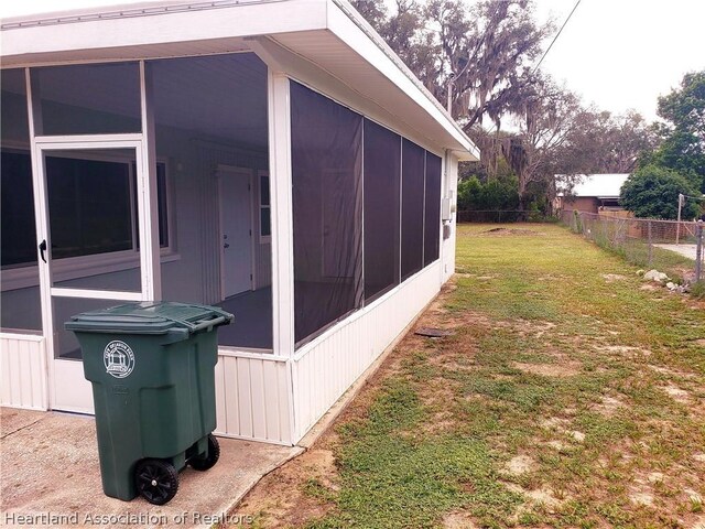 view of side of home featuring a lawn and a sunroom