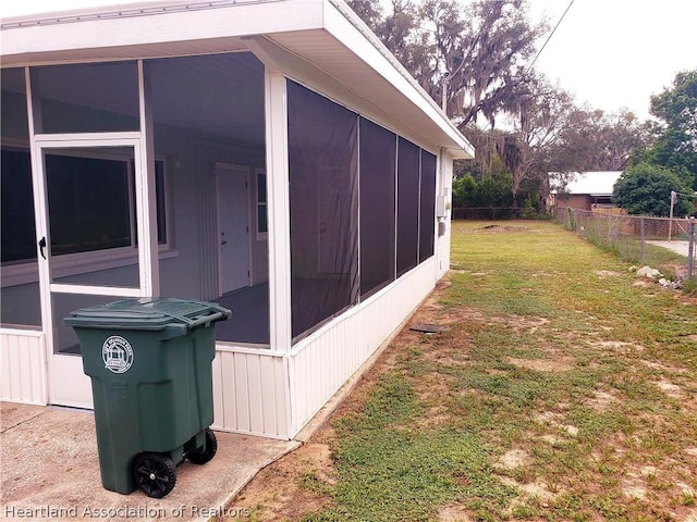 view of home's exterior with a yard, fence, and a sunroom