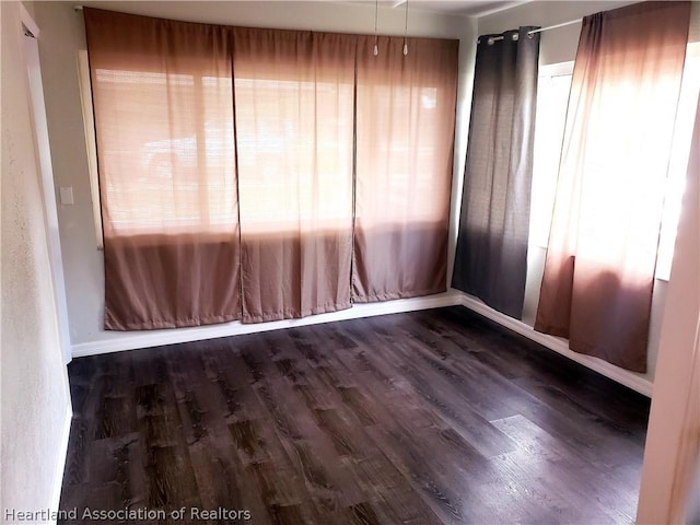 unfurnished room featuring baseboards and wood finished floors