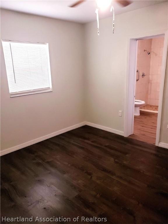 spare room with dark wood-style floors, baseboards, and a ceiling fan