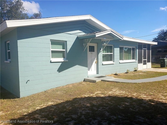 view of front of house with a front yard and a sunroom