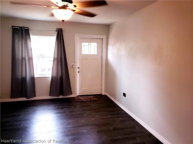 foyer entrance featuring a ceiling fan, baseboards, and dark wood-style flooring