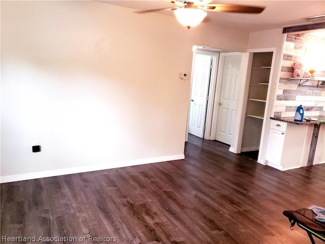 interior space with visible vents, baseboards, ceiling fan, and dark wood-type flooring