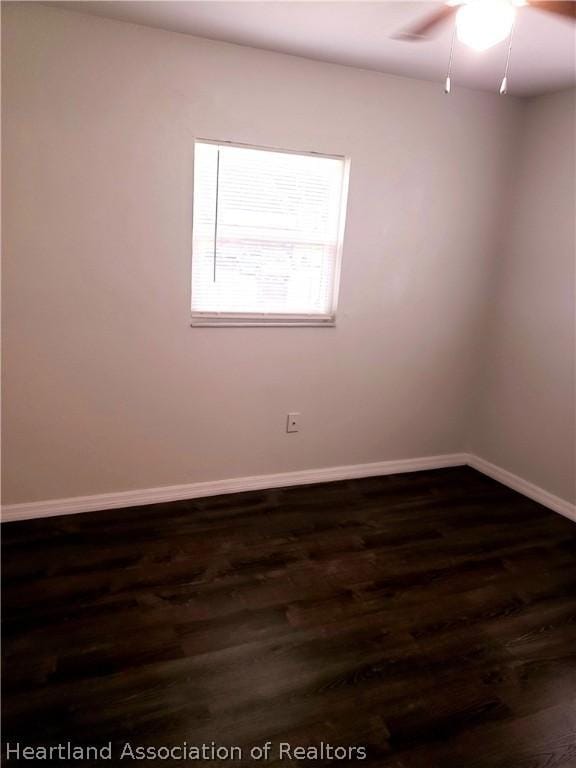 empty room featuring ceiling fan, baseboards, and dark wood finished floors