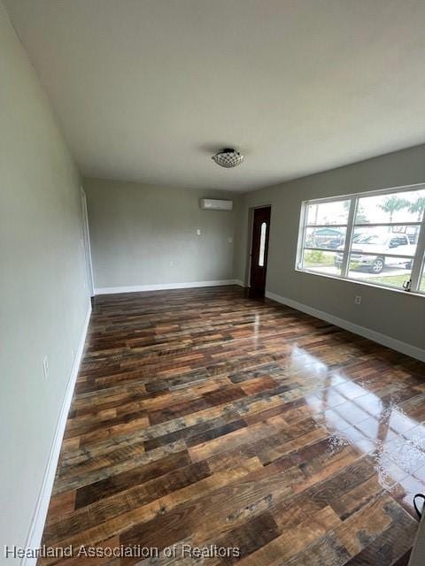 spare room featuring dark wood-type flooring and a wall mounted AC