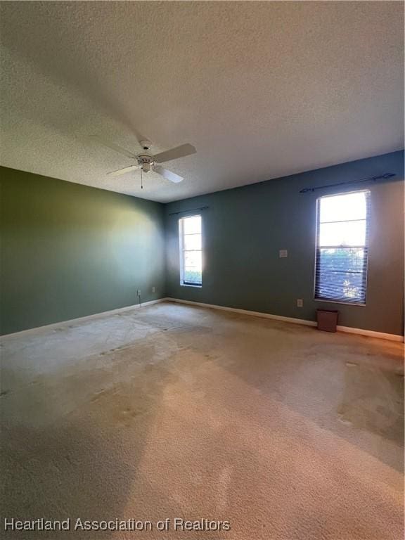 carpeted empty room featuring ceiling fan and a textured ceiling