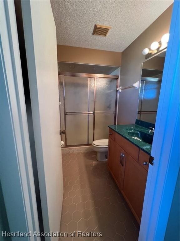 bathroom with vanity, a textured ceiling, tile patterned floors, and an enclosed shower