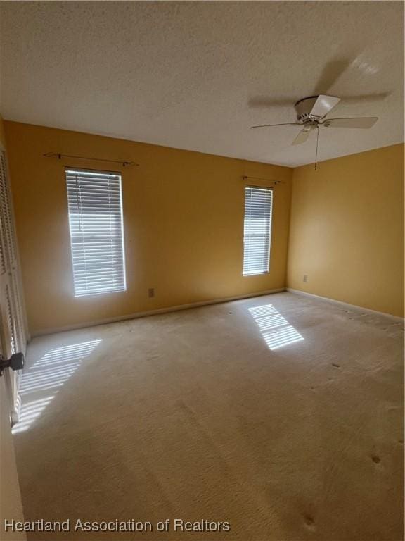 empty room featuring light carpet, a textured ceiling, and ceiling fan