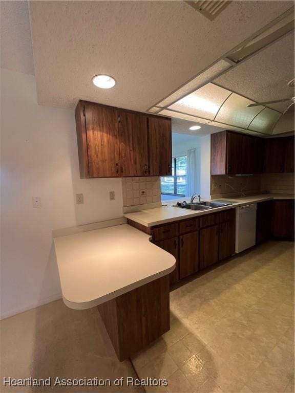 kitchen featuring kitchen peninsula, decorative backsplash, sink, dishwasher, and a breakfast bar area