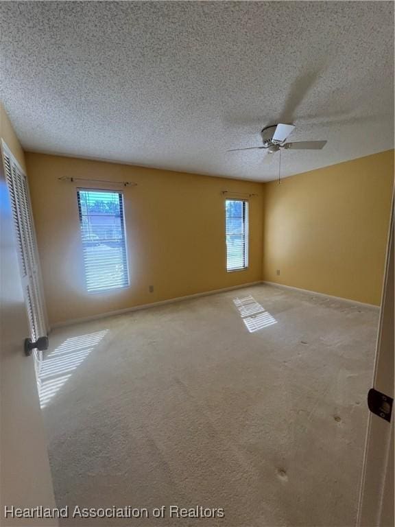 unfurnished room featuring carpet flooring, ceiling fan, and a textured ceiling