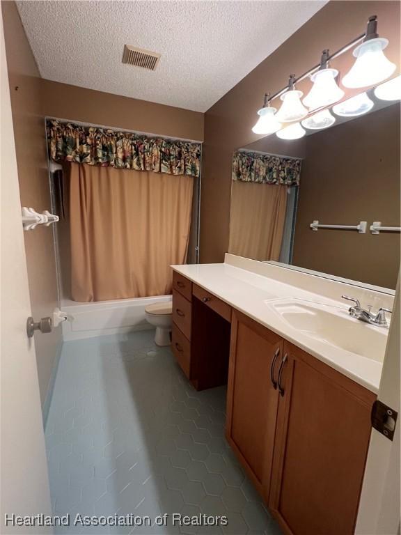 full bathroom featuring tile patterned flooring, a textured ceiling, toilet, vanity, and shower / tub combo