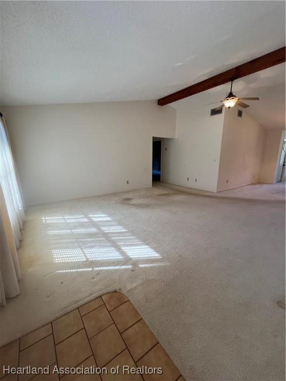 empty room with vaulted ceiling with beams, ceiling fan, and light colored carpet