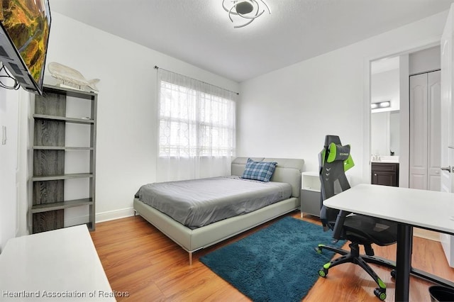 bedroom with ensuite bath and light wood-type flooring