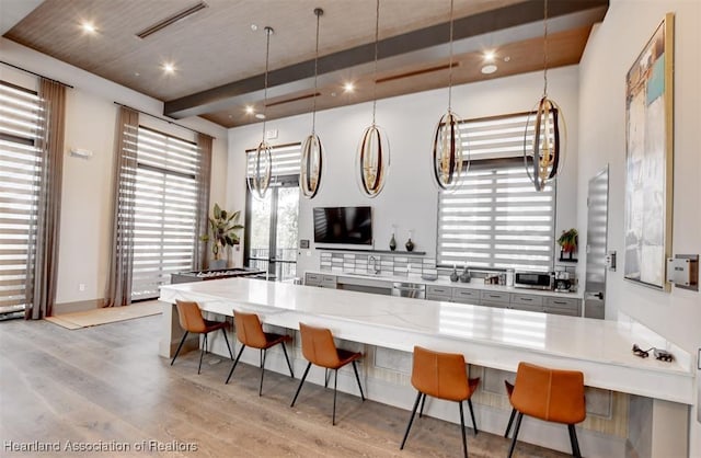 kitchen with a kitchen bar, decorative light fixtures, light wood-type flooring, and kitchen peninsula