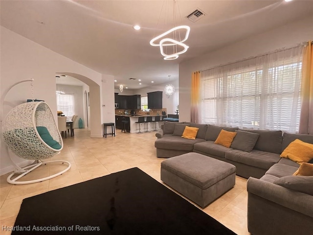 living room with a healthy amount of sunlight, light tile patterned floors, and a chandelier