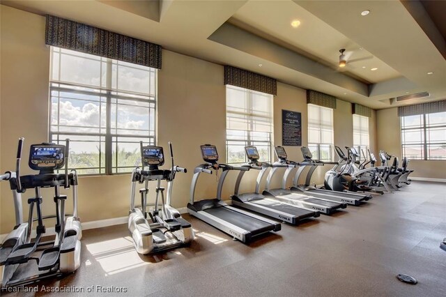 workout area featuring ceiling fan and a raised ceiling