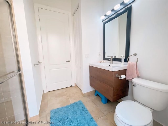 bathroom with tile patterned flooring, vanity, an enclosed shower, and toilet