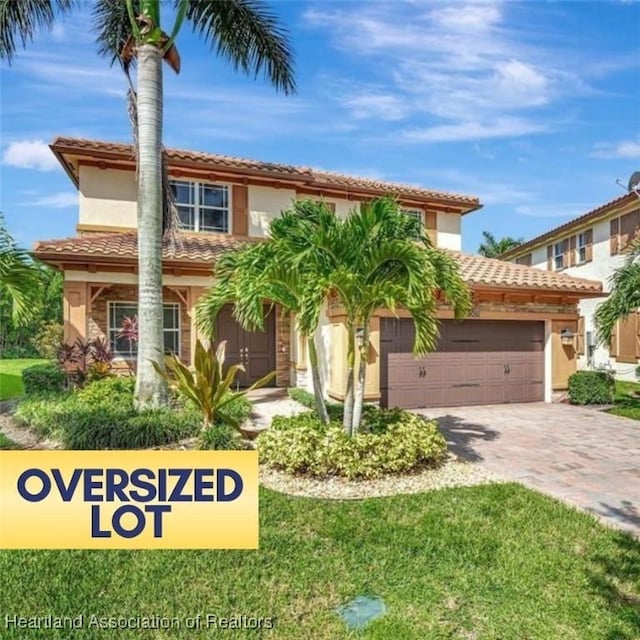 mediterranean / spanish-style house featuring a garage and a front lawn