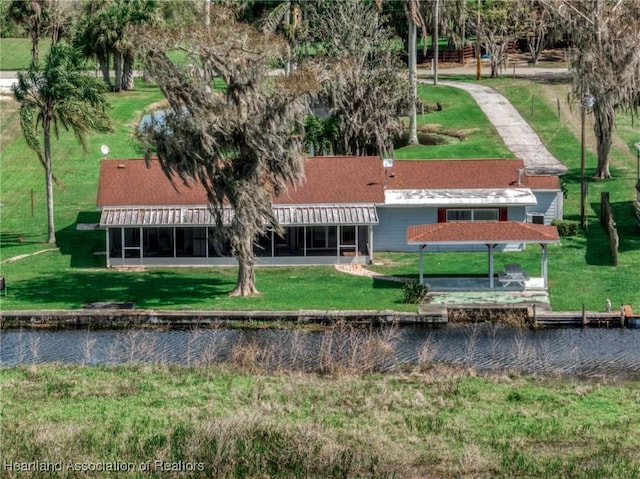 back of property with a lawn and a water view