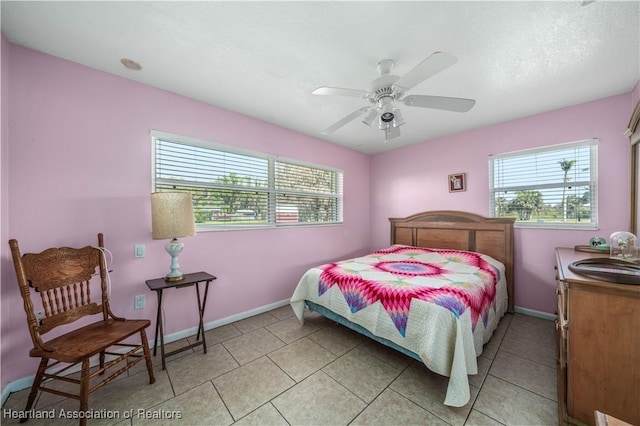 bedroom featuring light tile patterned floors, ceiling fan, a sink, and baseboards
