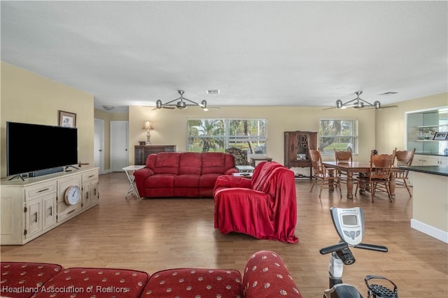 living area with visible vents, baseboards, a ceiling fan, and light wood-style floors