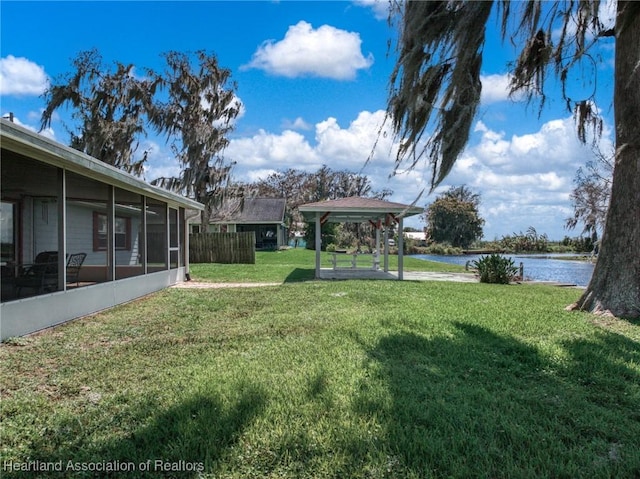 view of yard with a water view, a sunroom, and fence