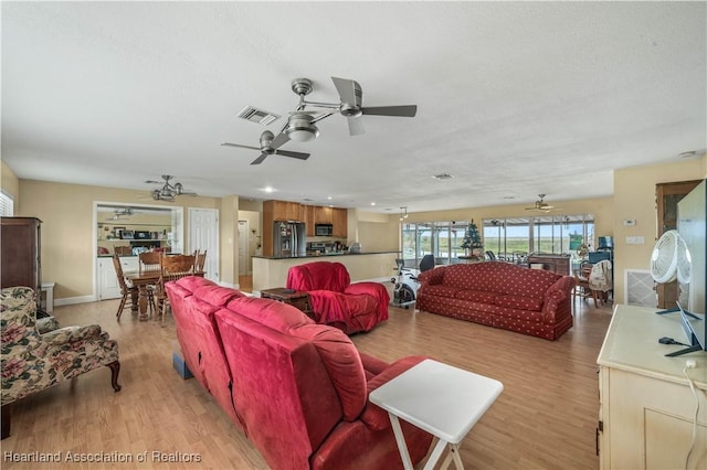 living room featuring visible vents, ceiling fan, and light wood-style flooring
