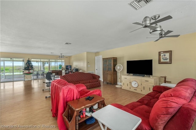 living room with wood finished floors, visible vents, and a ceiling fan
