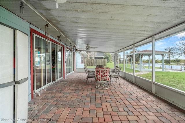 unfurnished sunroom with ceiling fan and a water view