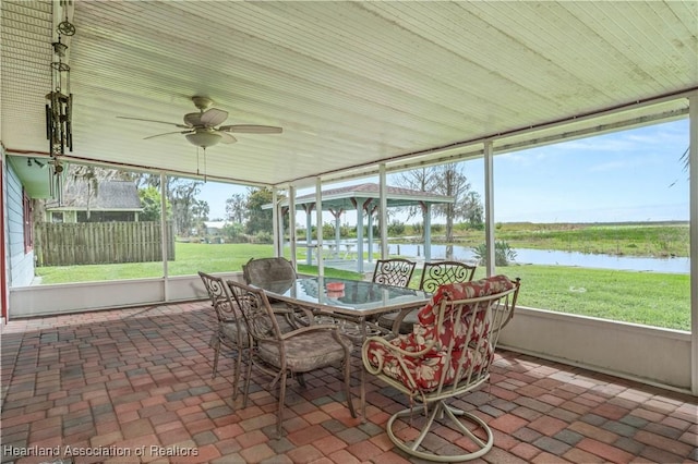 sunroom / solarium featuring a water view and ceiling fan