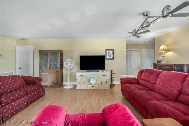 living room with wood finished floors, a ceiling fan, and baseboards
