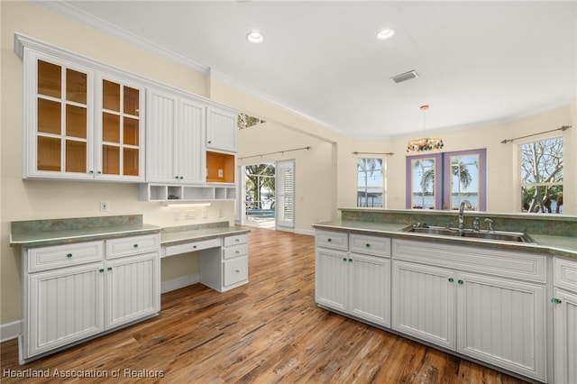 kitchen featuring hardwood / wood-style flooring, sink, pendant lighting, and white cabinets