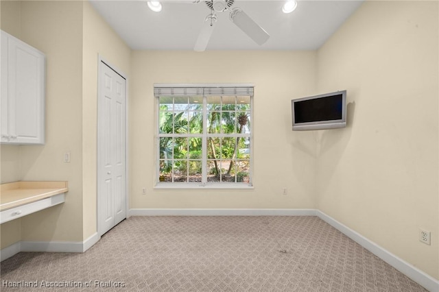 interior space with light carpet, ceiling fan, and built in desk