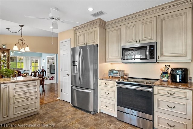 kitchen featuring stainless steel appliances, cream cabinets, hanging light fixtures, and stone counters