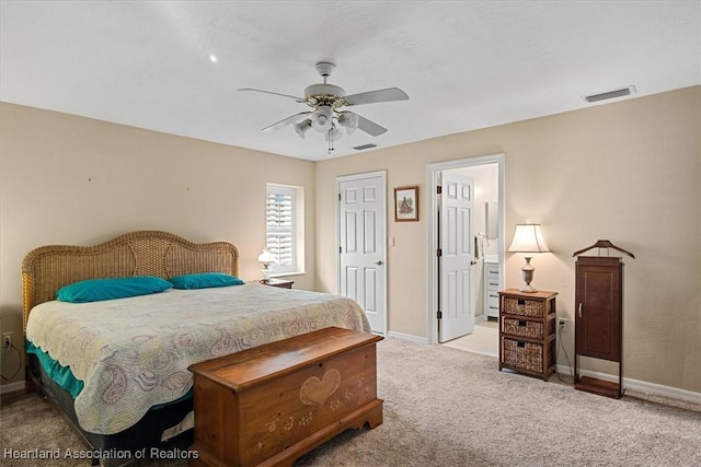 bedroom featuring ensuite bath, light colored carpet, and ceiling fan